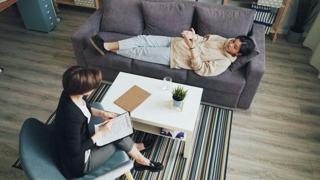 Treatments A psychotherapy session with a therapist consulting a client indoors on a sofa.